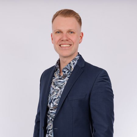 Sachverständiger Elias Barlag Mann in Anzug mit offenem Hemdkragen und Muster, lächelt freundlich.