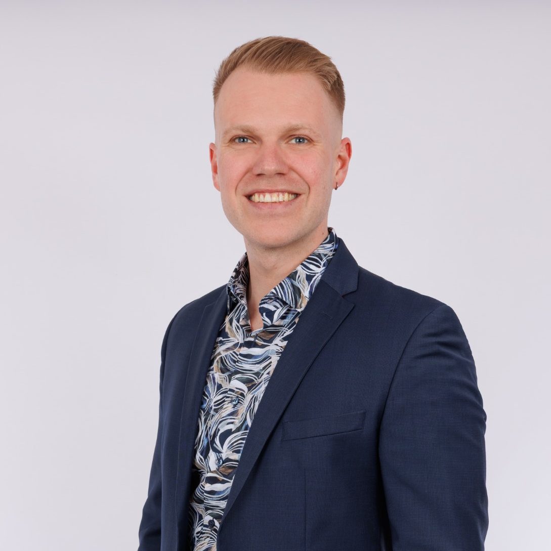 Sachverständiger Elias Barlag Mann in Anzug mit offenem Hemdkragen und Muster, lächelt freundlich.